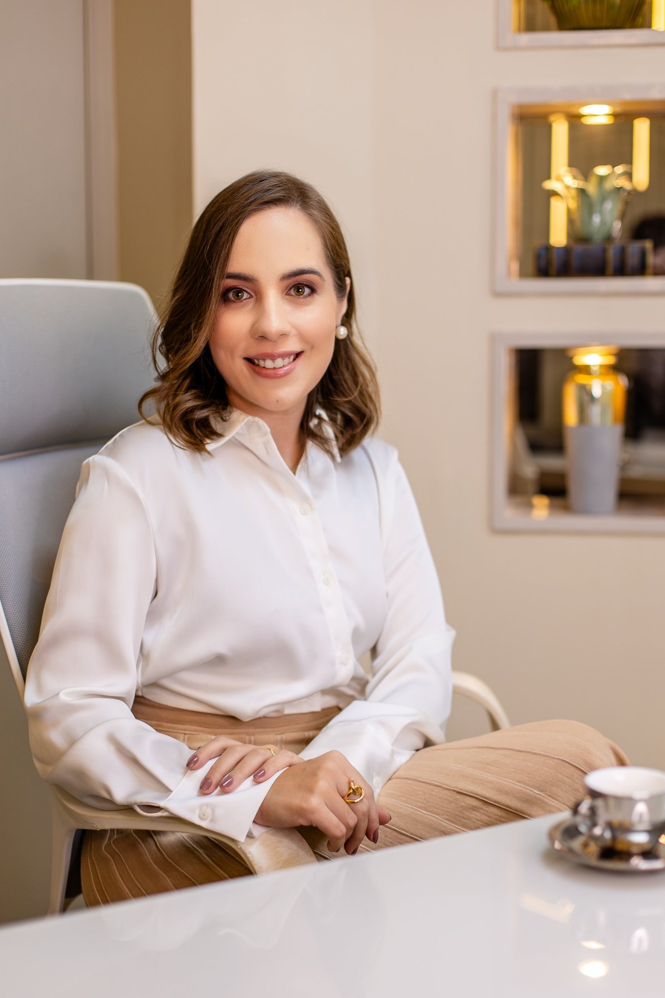 Dra. Marina Cedro, médica endocrinologista em Salvador, sentada em seu consultório, de camisa branca, sorrindo para a câmera
